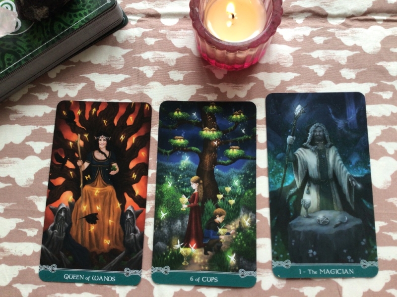 3 tarot cards and a candle on a tarot cloth